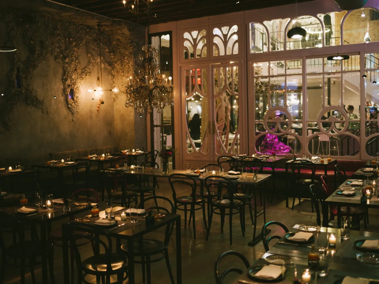Candlelit dining room at abc Kitchen with chandeliers and set tables.